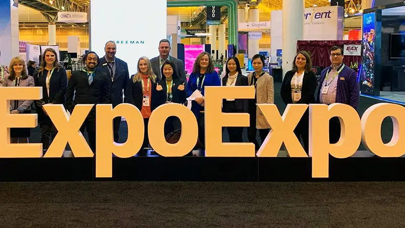 students standing in front of an Expo Expo large sign